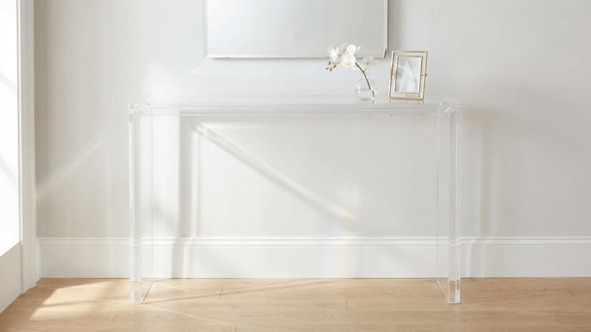 transparent acrylic console table with glass vase and brass frame creating airy see-through effect