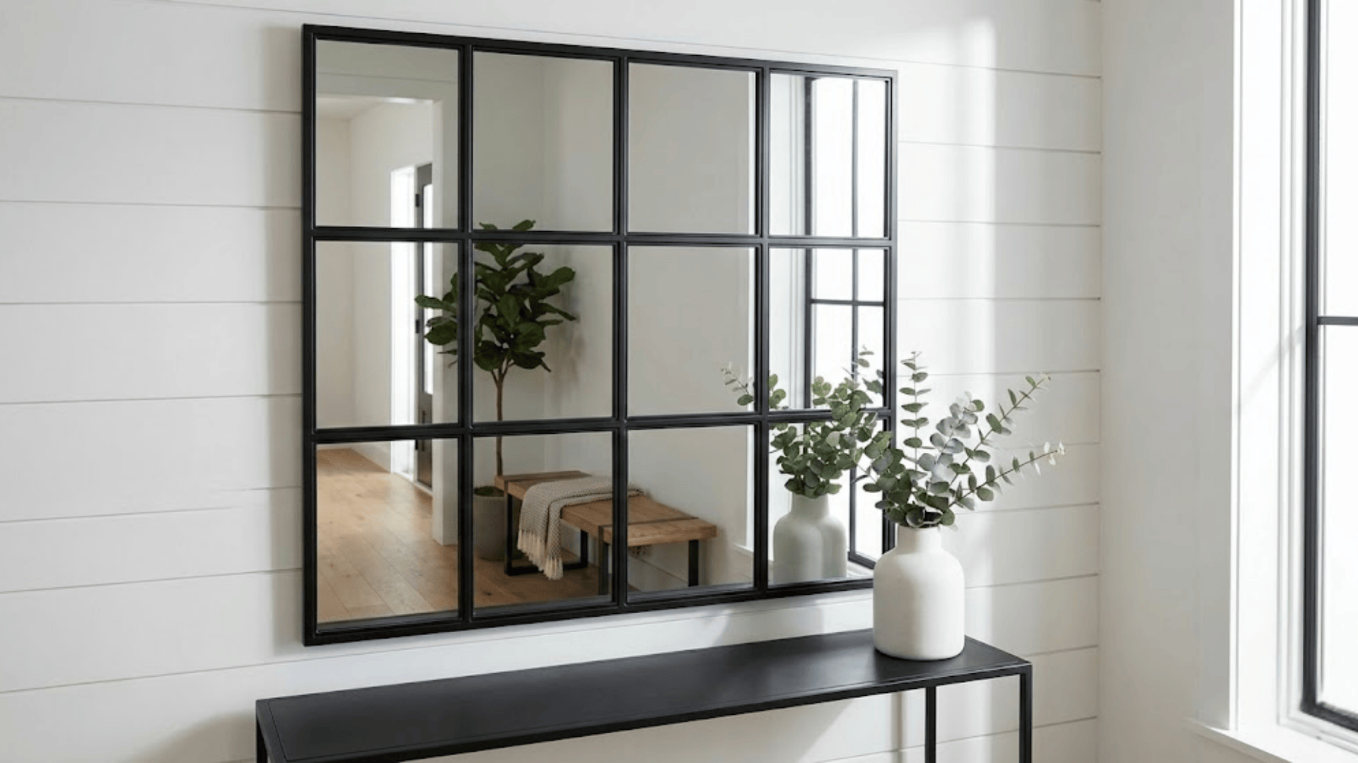 black metal grid mirror with windowpane design above narrow console creating industrial modern look