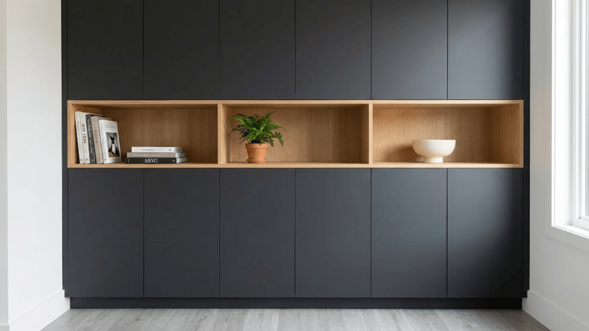 storage wall combining closed charcoal cabinets with open oak shelves holding books plant and bowl