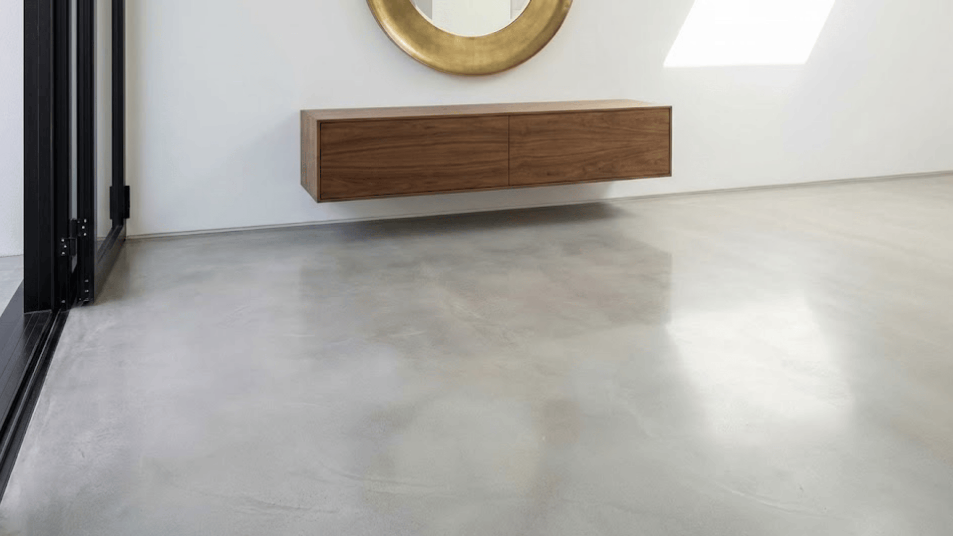 polished concrete floor in light gray with smooth matte finish and floating walnut console above