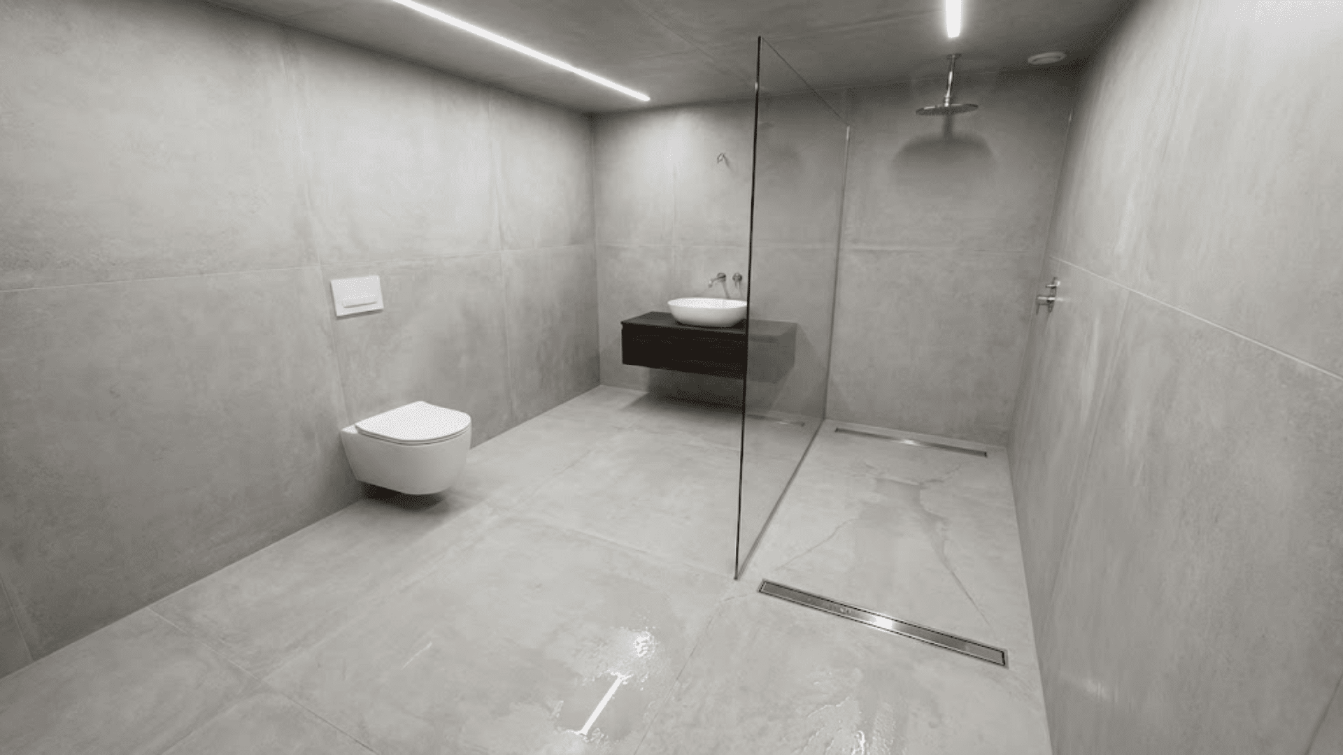 european wet room bathroom with doorless shower and waterproofed concrete-look tiles throughout