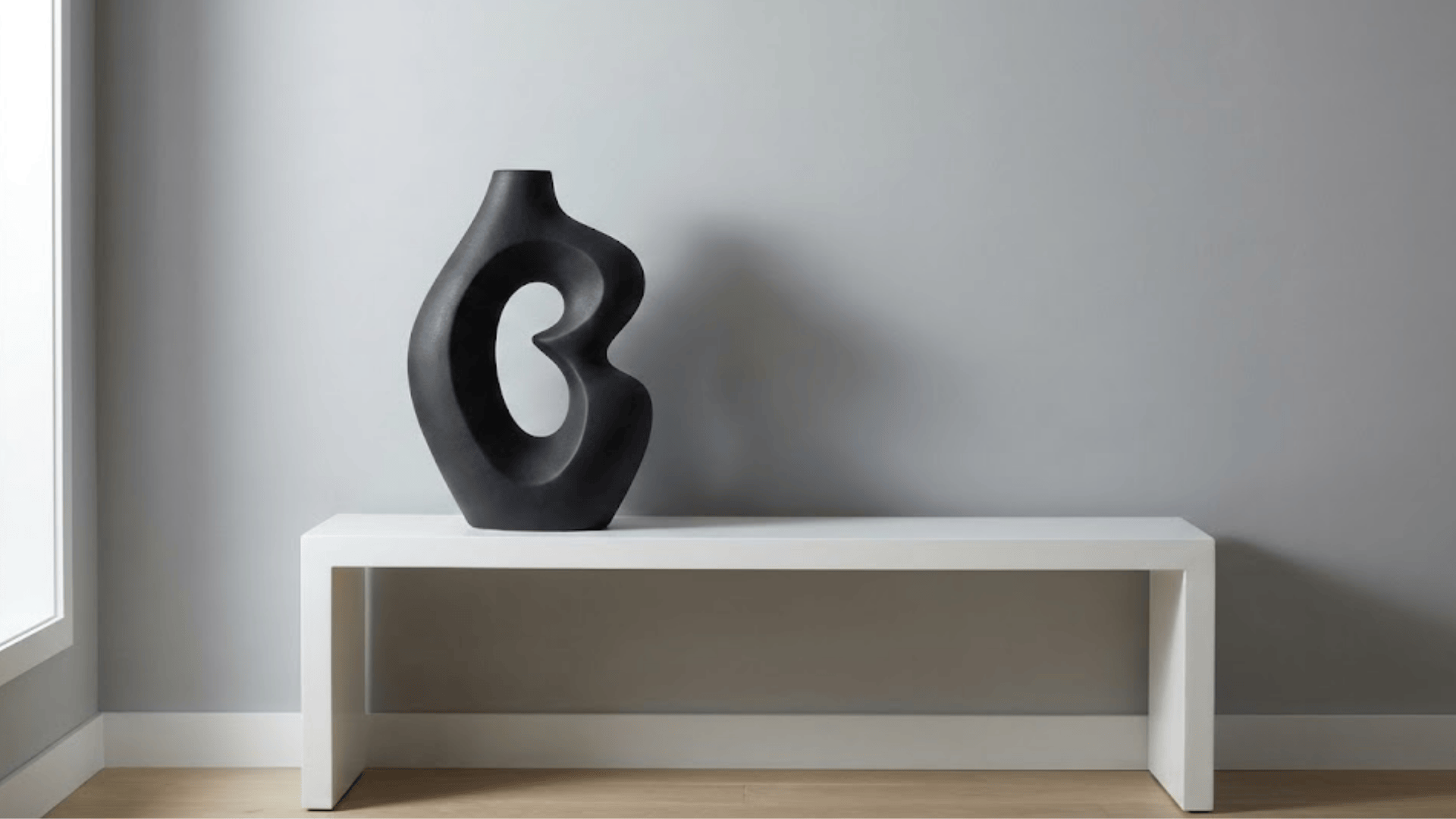 single bold black ceramic sculpture on white console with organic curves and negative space design