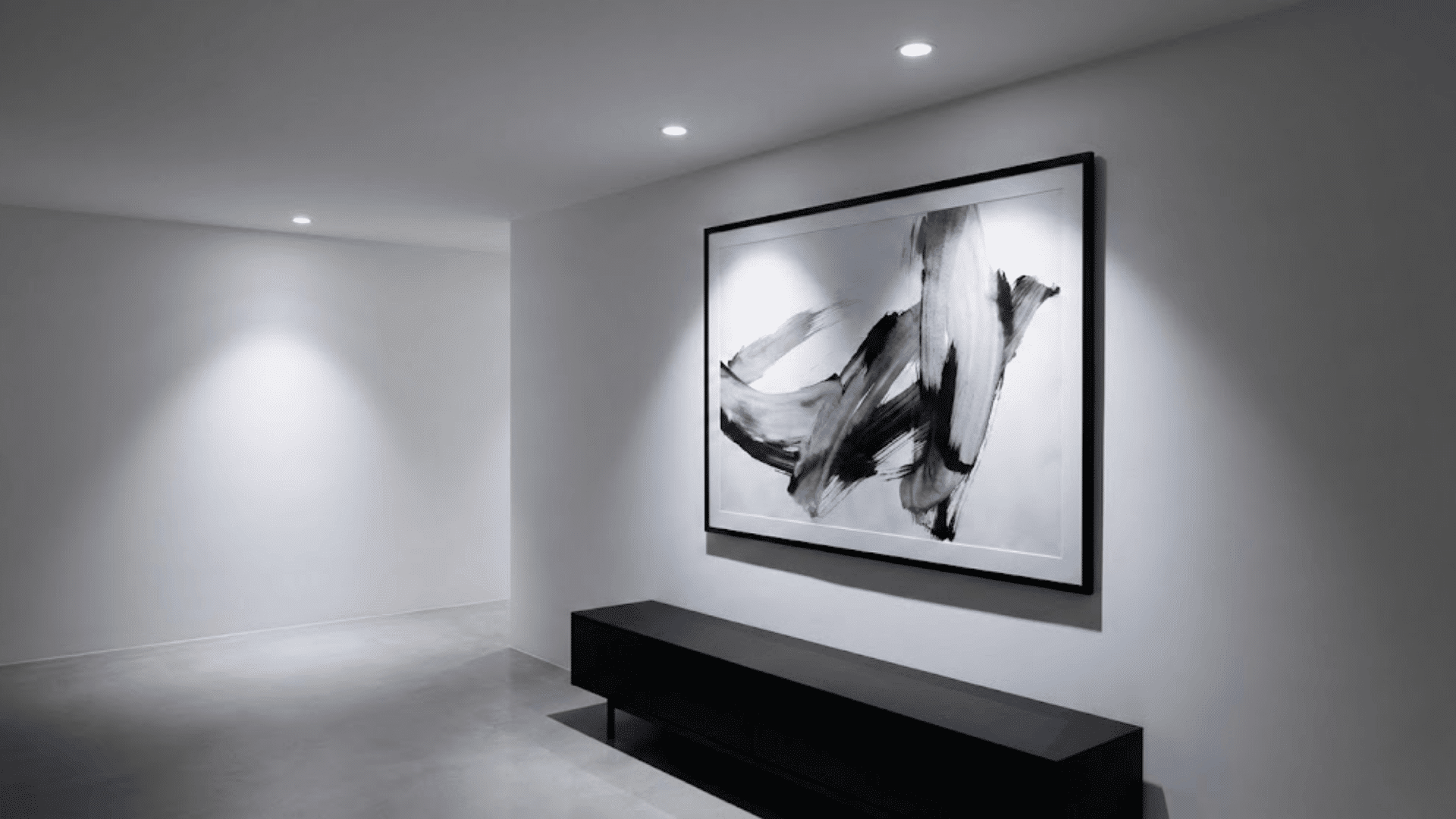 recessed led downlights in white ceiling illuminating black framed artwork with gallery style effect