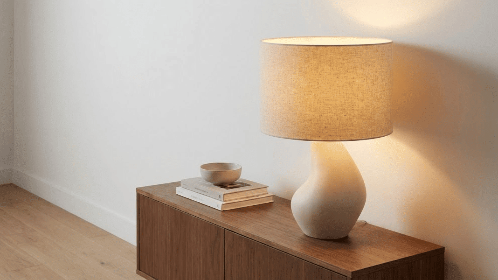 sculptural ceramic table lamp with curved base and linen shade on wooden console creating warm light