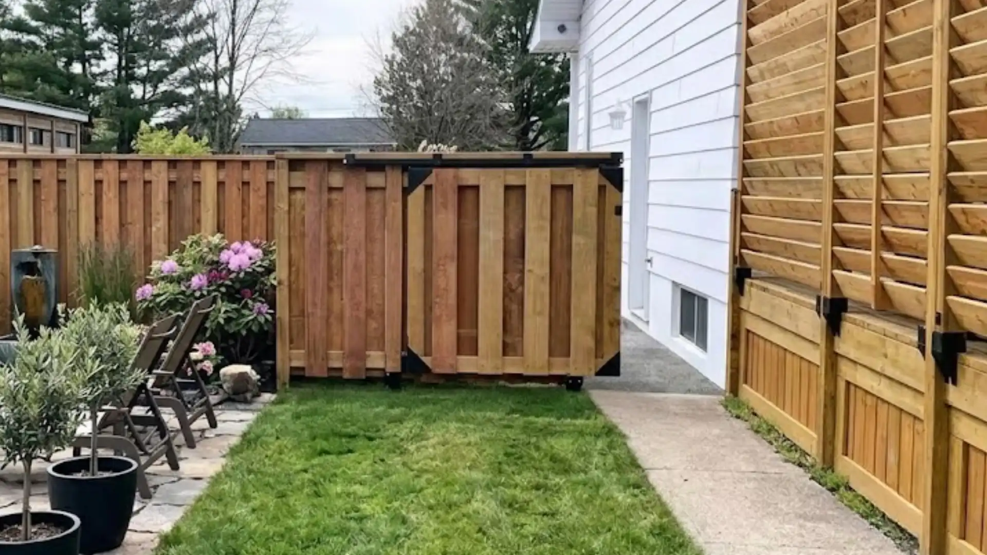 sliding panel privacy fence with movable wooden sections around a modern backyard patio area