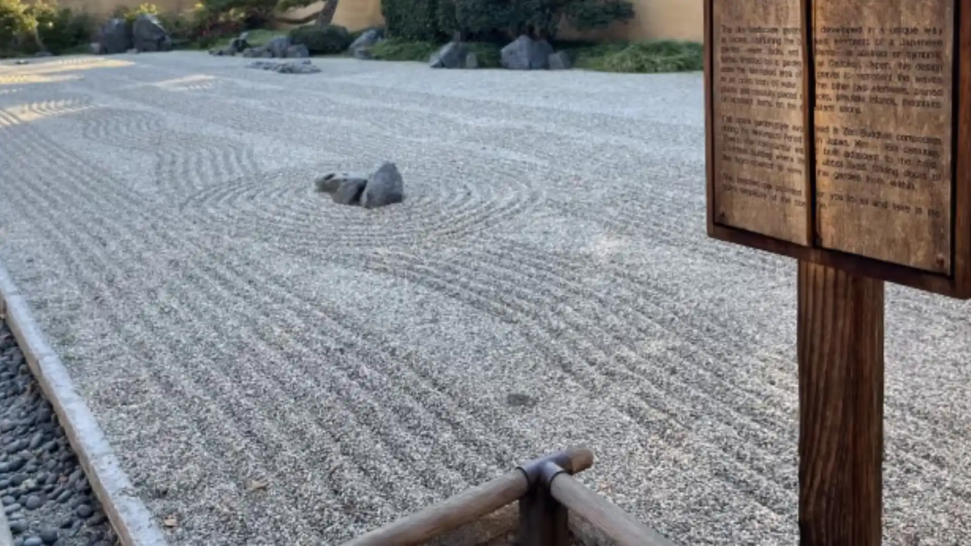 raked gravel surrounds stone groupings with flowing patterns and a wooden sign nearby