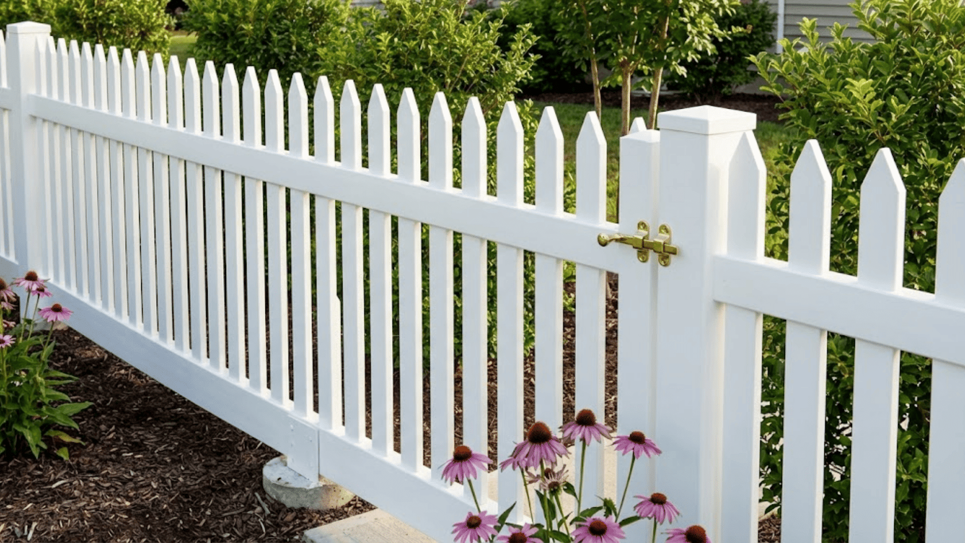 freshly painted white picket fence with flowers growing at the base