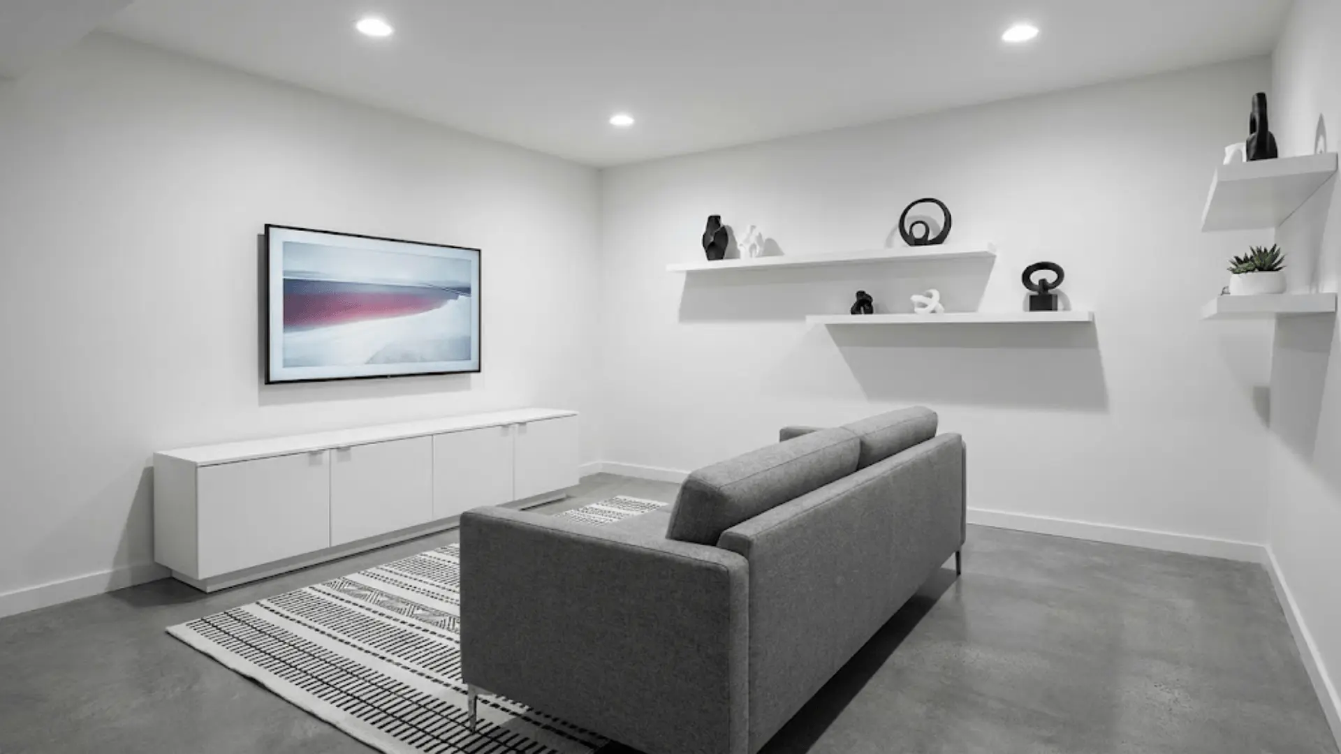 minimalist monochrome game room with white walls, gray furniture, and clean lines with hidden storage