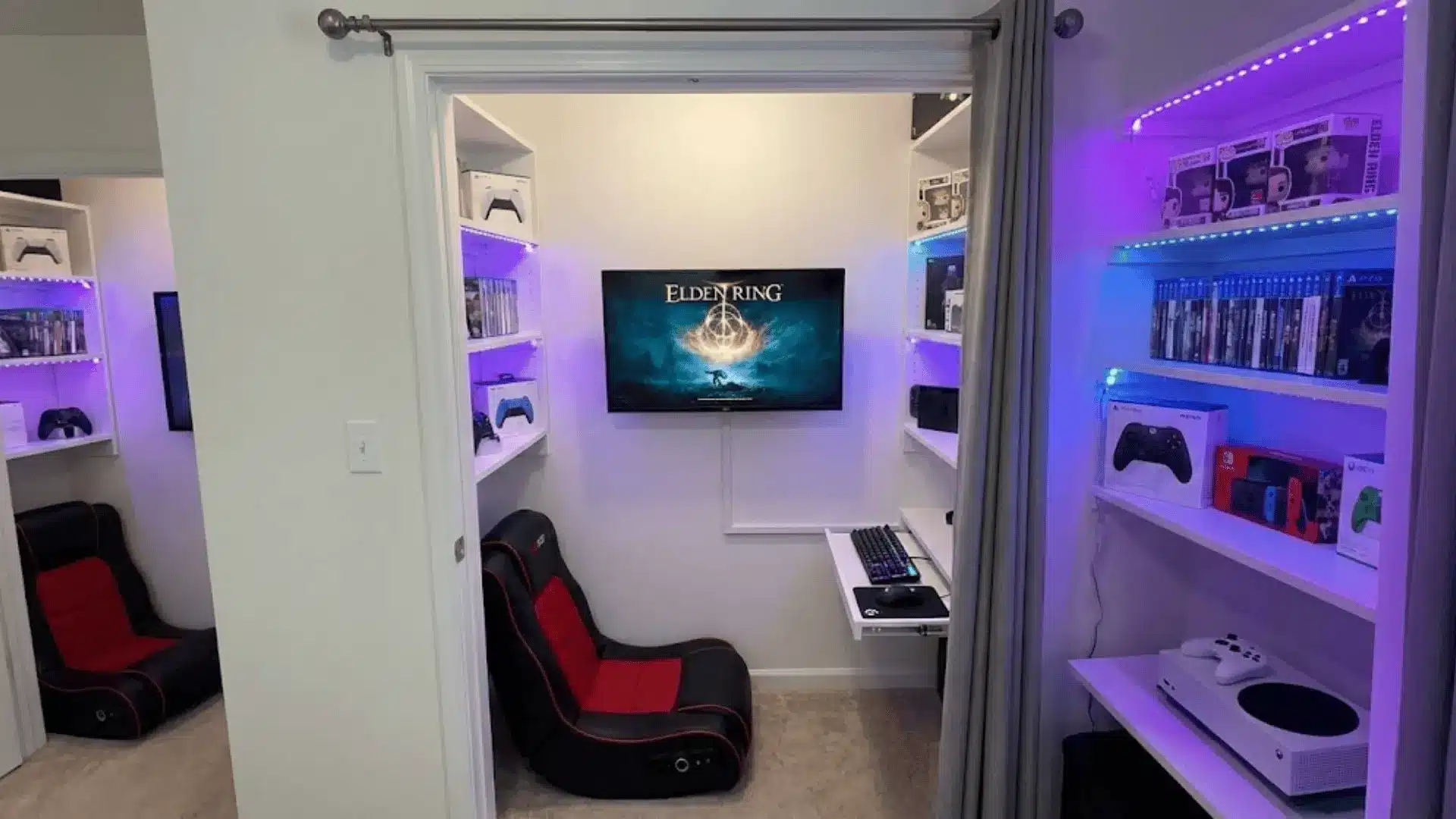 walk-in closet converted to mini gaming room with wall-mounted screen and shelving for game storage