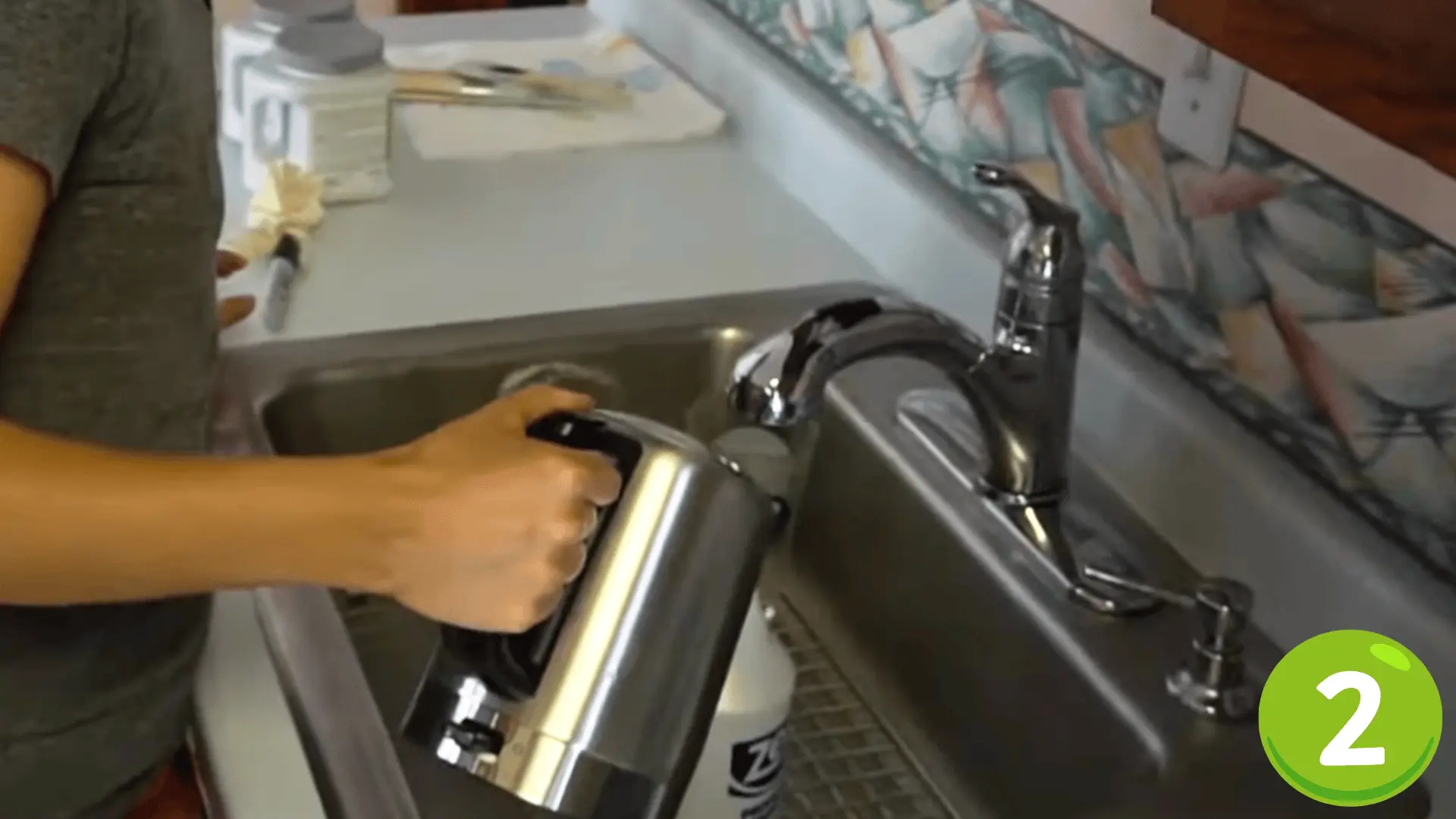a person filling a wallpaper steamer with water at a kitchen sink to prepare the removal solution