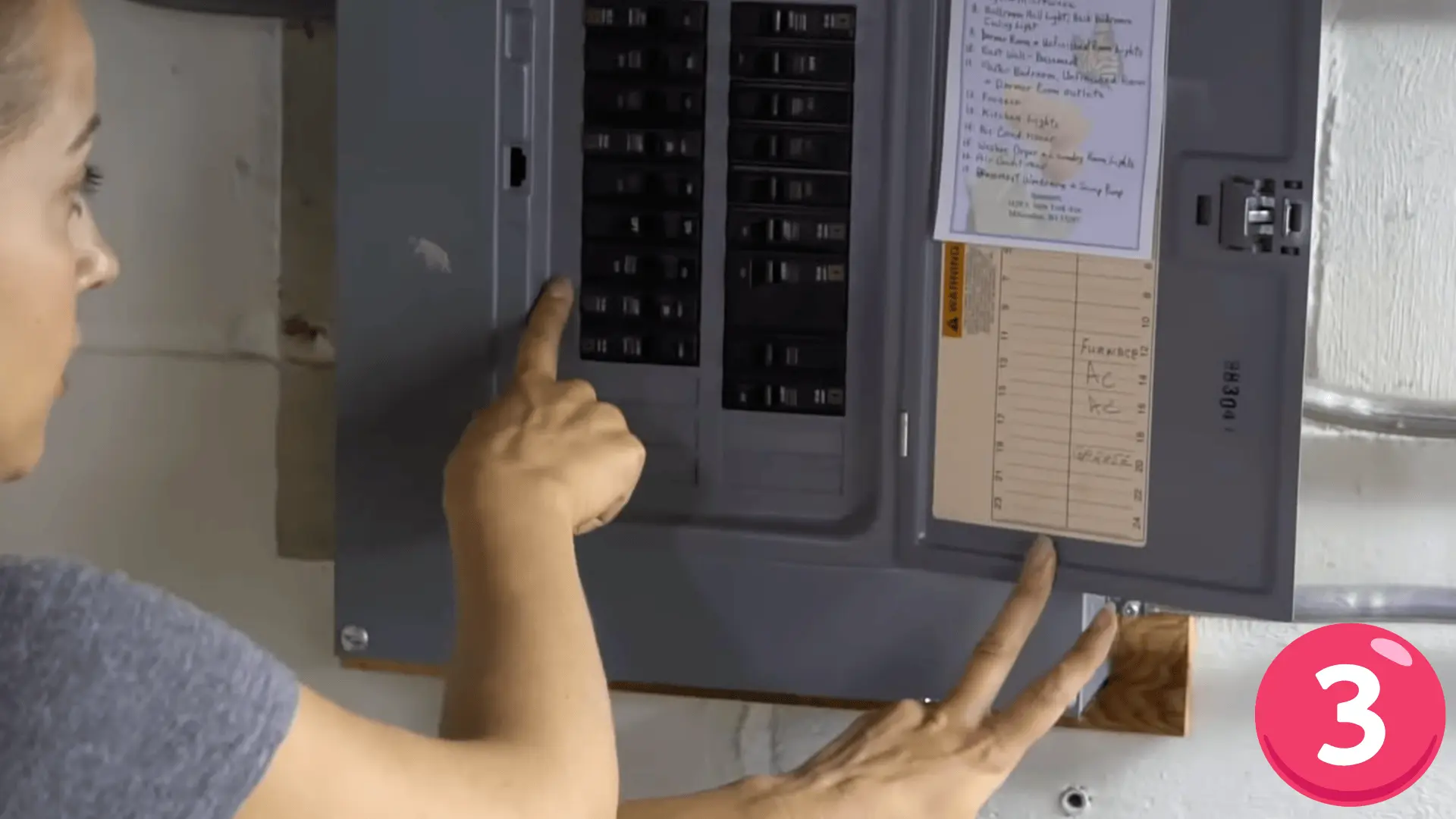 a person pointing at a labeled circuit breaker box to locate and turn off the correct electrical switch