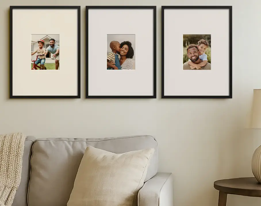 Three black-framed family photos on wall above beige sofa with cushions and knit throw