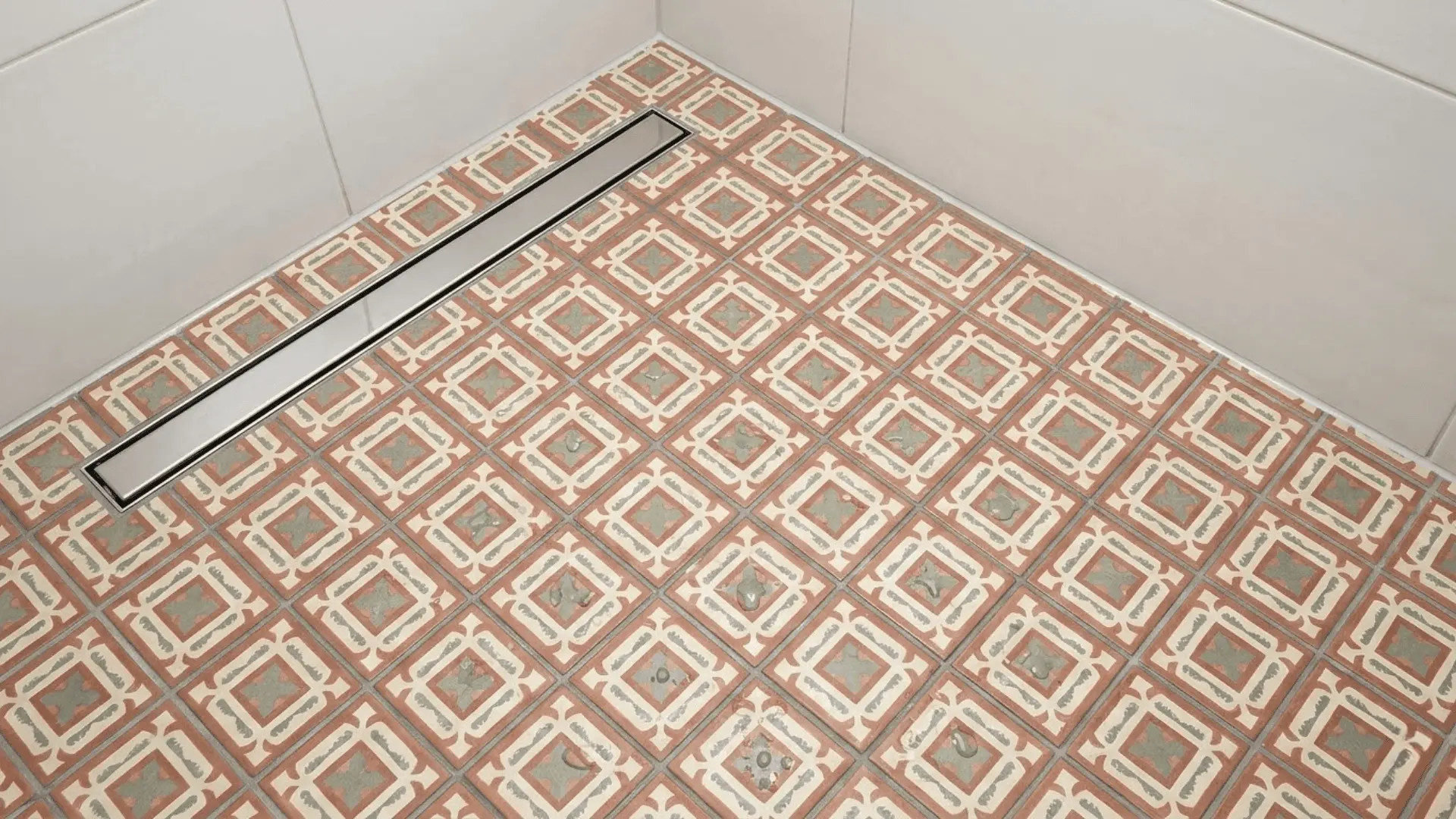 geometric encaustic shower floor tiles in terracotta and sage with chrome linear drain