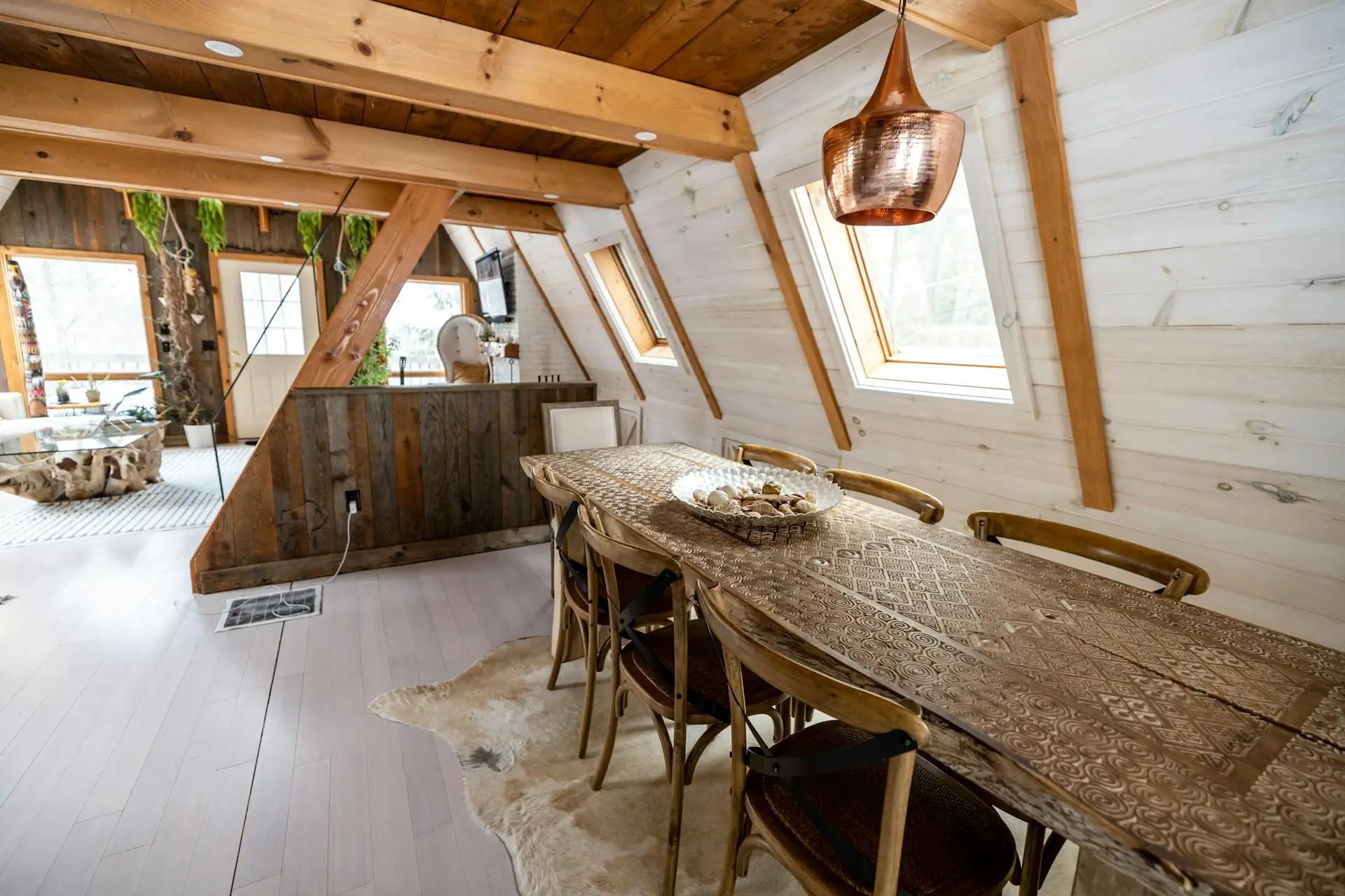 Rustic dining area with wooden table and chairs in cozy cabin setting with skylights