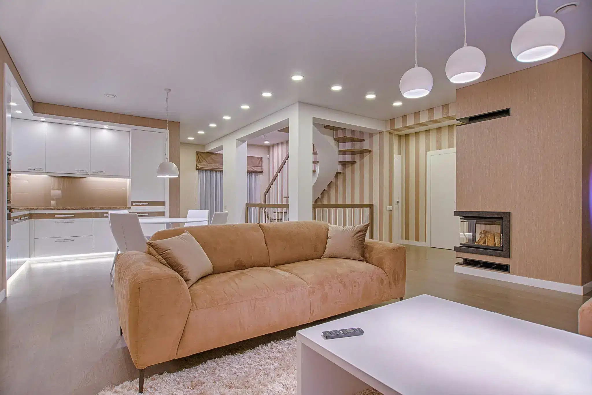 Spacious modern living room with beige sofa, white furniture, and warm lighting
