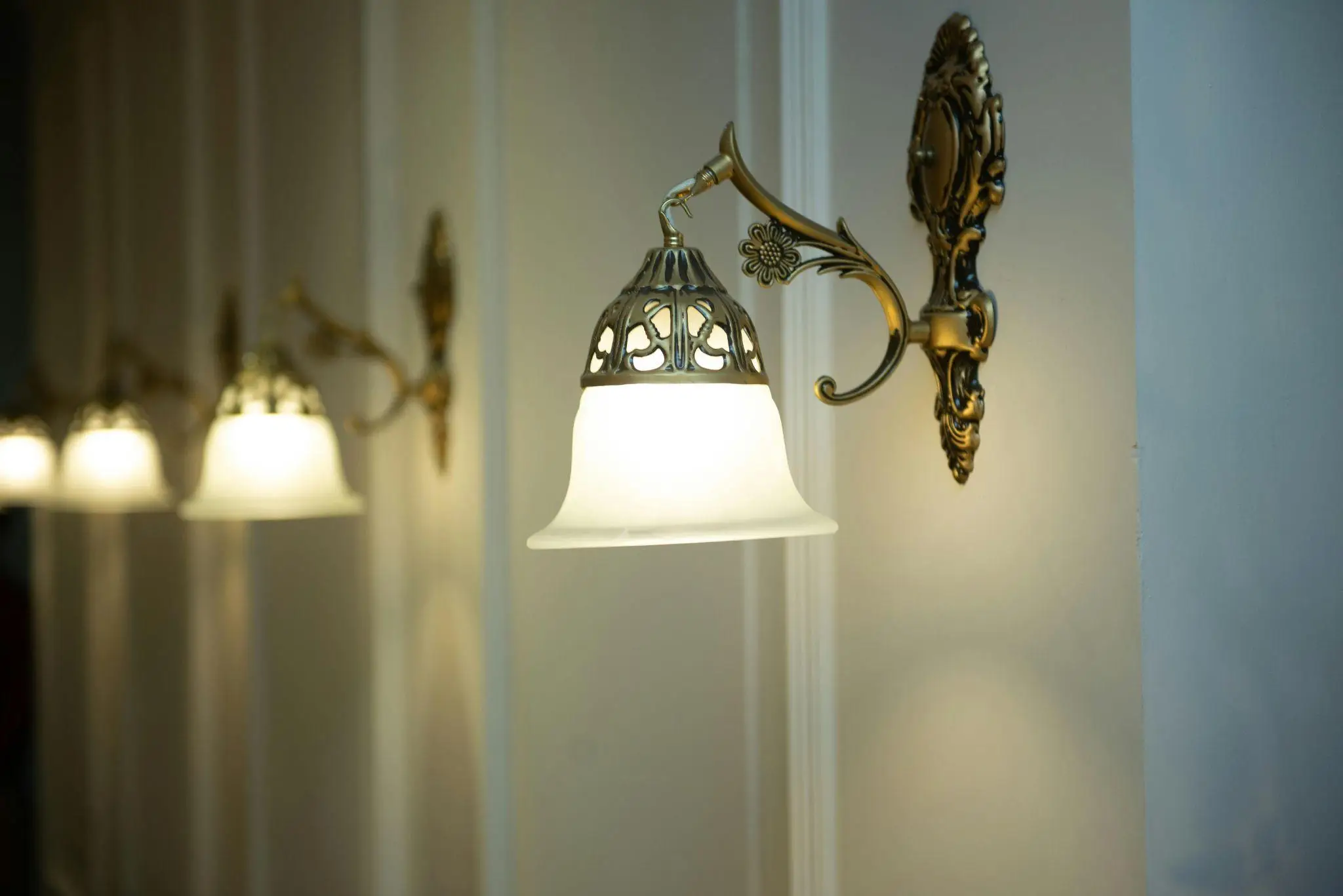 Antique brass wall sconces with frosted glass shades in a softly lit interior hallway