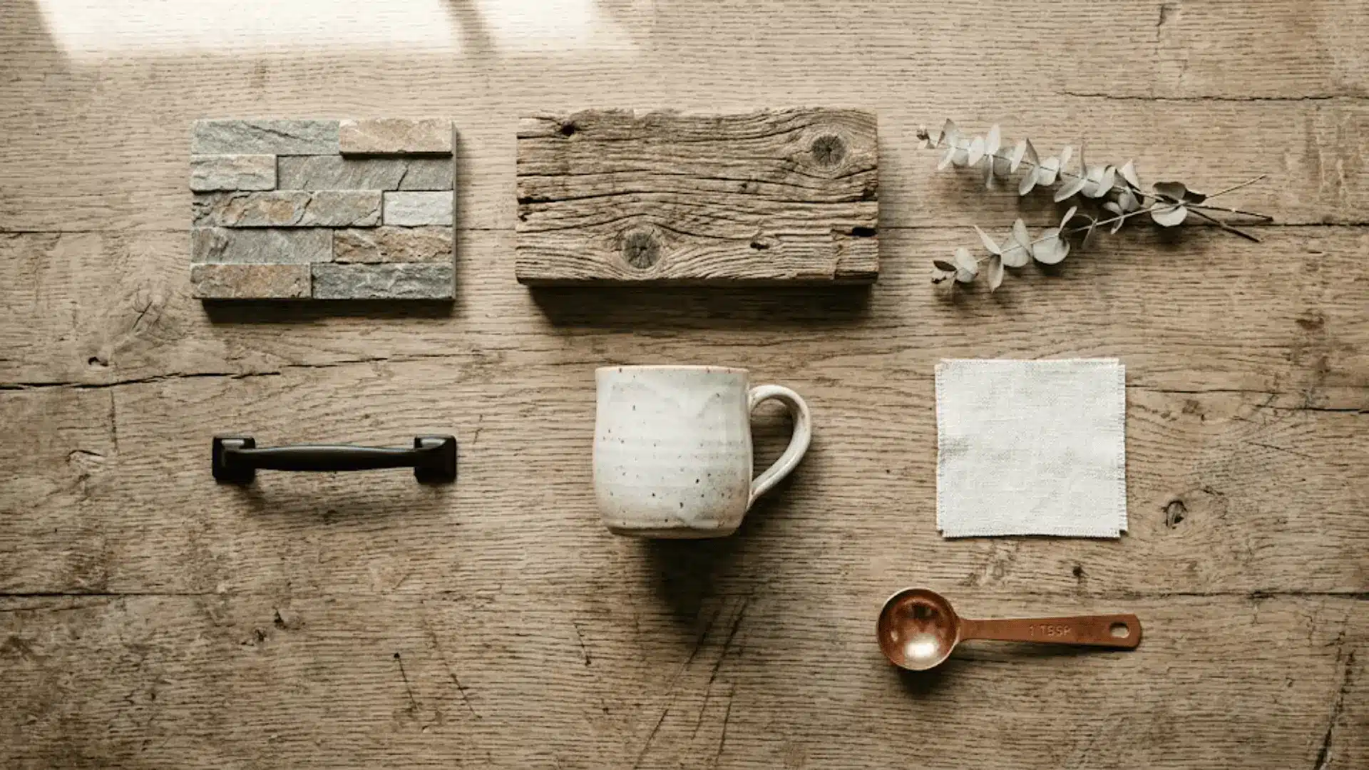 flat-lay of barndominium kitchen materials including reclaimed wood, stone tile, matte black hardware, and ceramic on oak