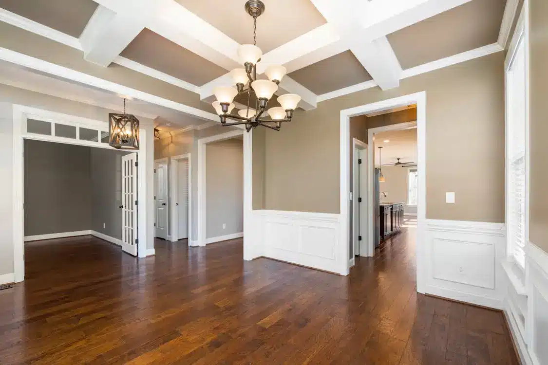 Spacious room with dark wood floor, beige walls, and elegant chandelier ceiling light