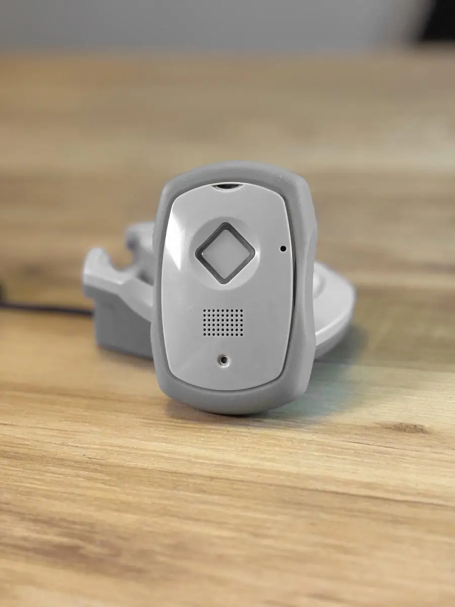 Gray medical alert device on wooden surface in soft lighting environment
