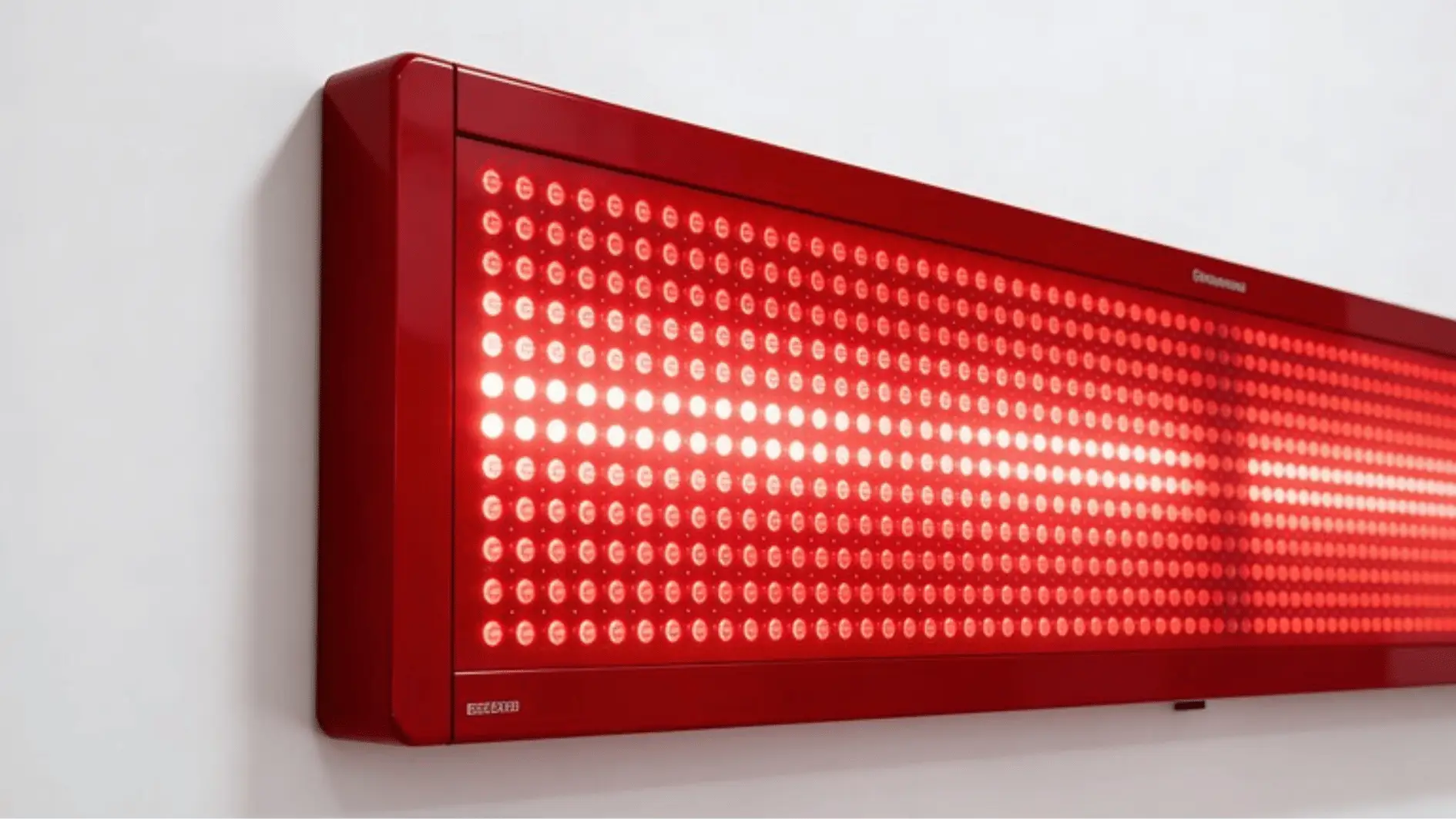 Red LED light therapy panel mounted on a white wall indoors
