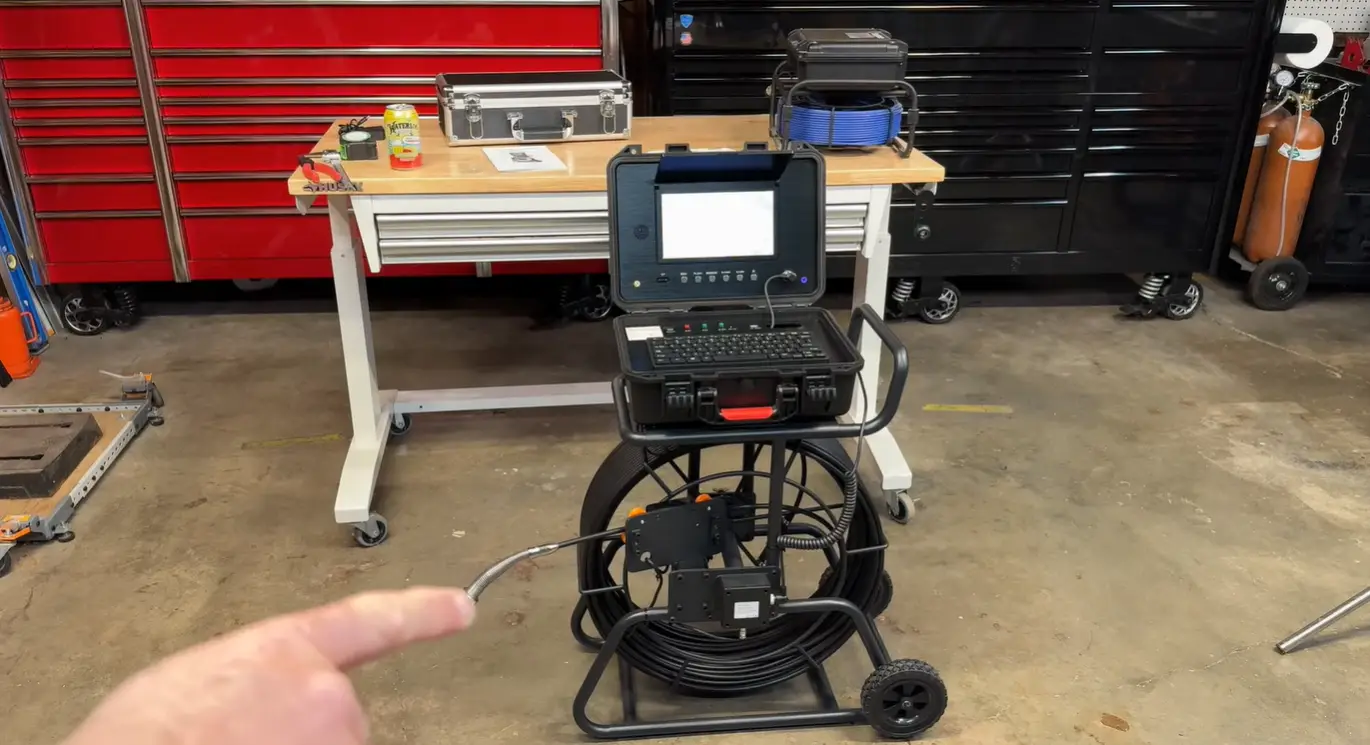 Industrial inspection camera setup on wheeled stand in workshop with red tool chest