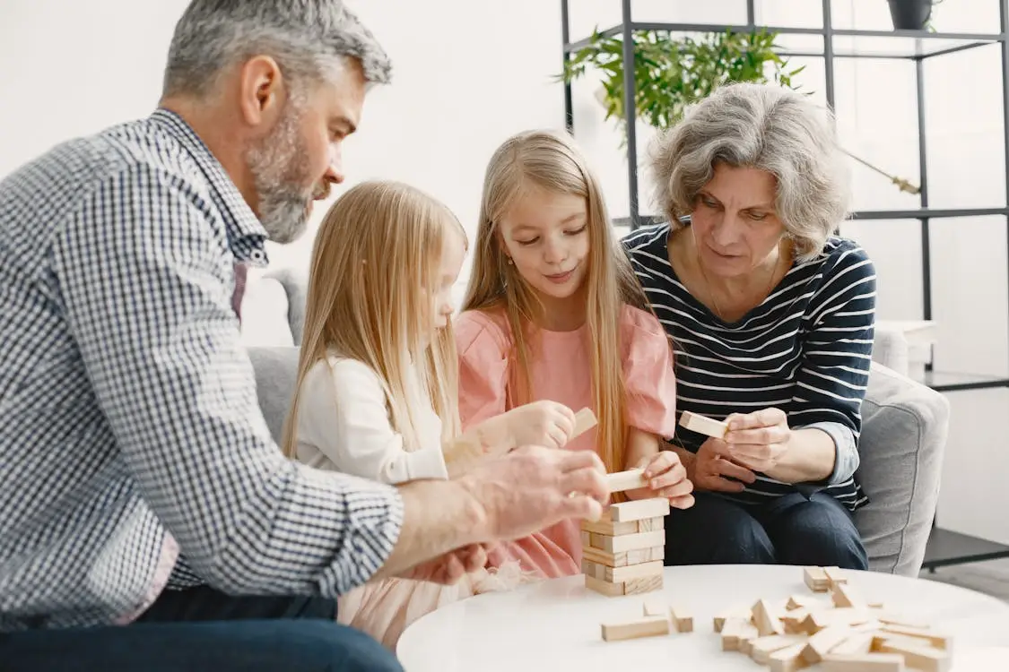 Family playing with wooden blocks at a white table in a bright living room