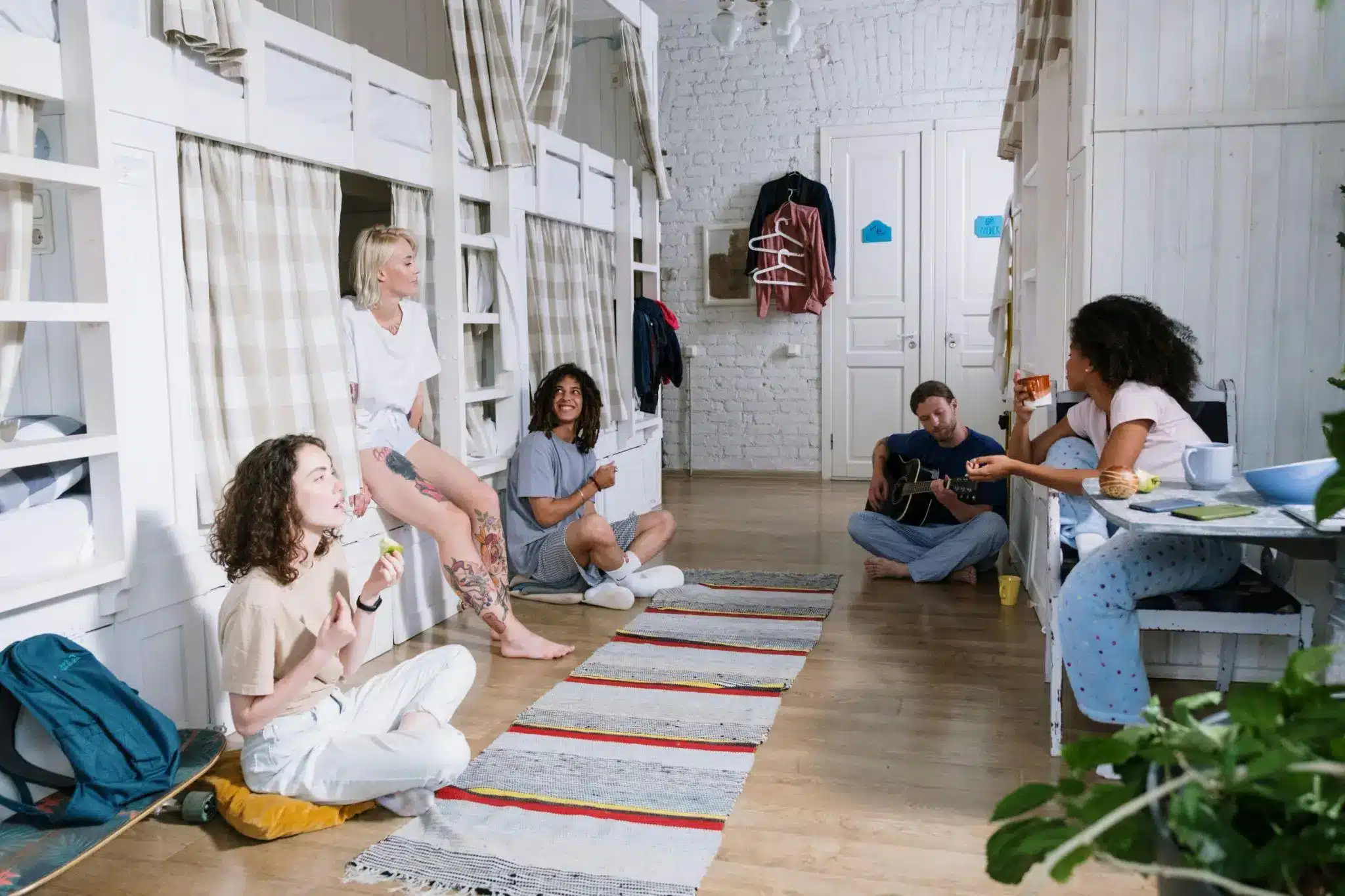 People relaxing in cozy shared bedroom with bunk beds and wooden flooring
