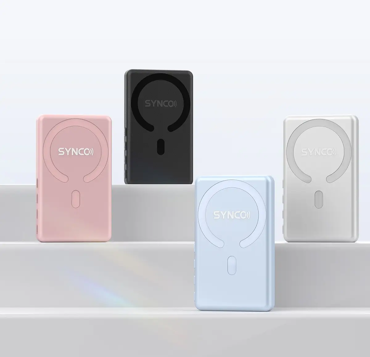 Four wireless microphone transmitters in pastel colors on minimalist white background