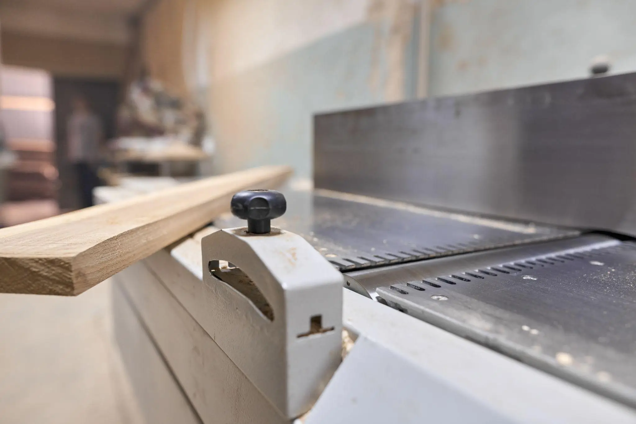 Wooden plank resting on industrial saw table in a dusty workshop setting