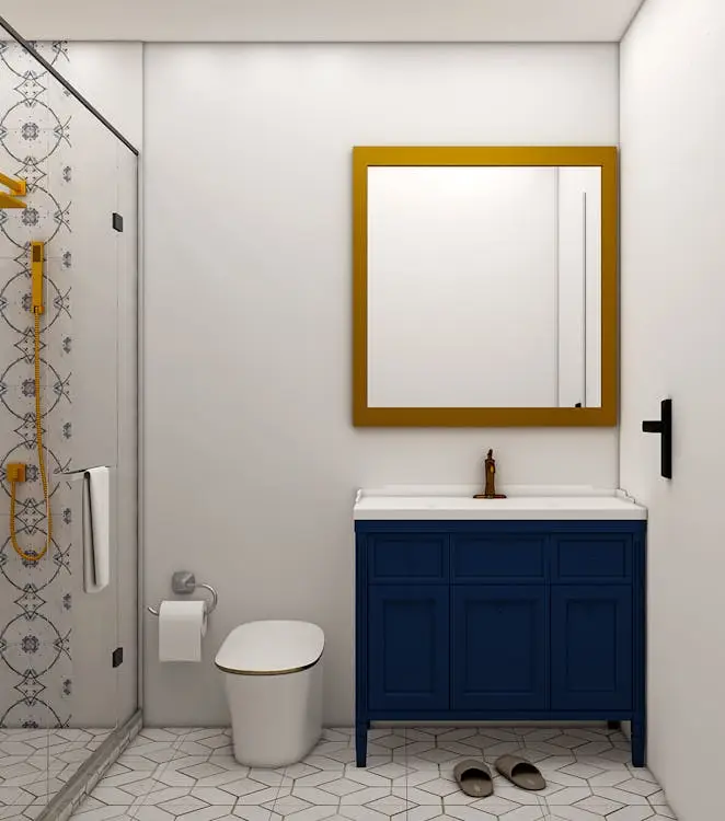 Modern bathroom with blue vanity, gold-framed mirror, and patterned shower tiles