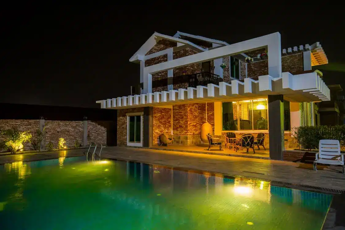Modern two-story house with brick facade and pool illuminated at night