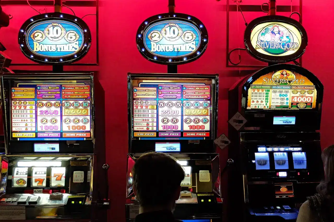Illuminated slot machines in a casino with a person playing under dim lighting