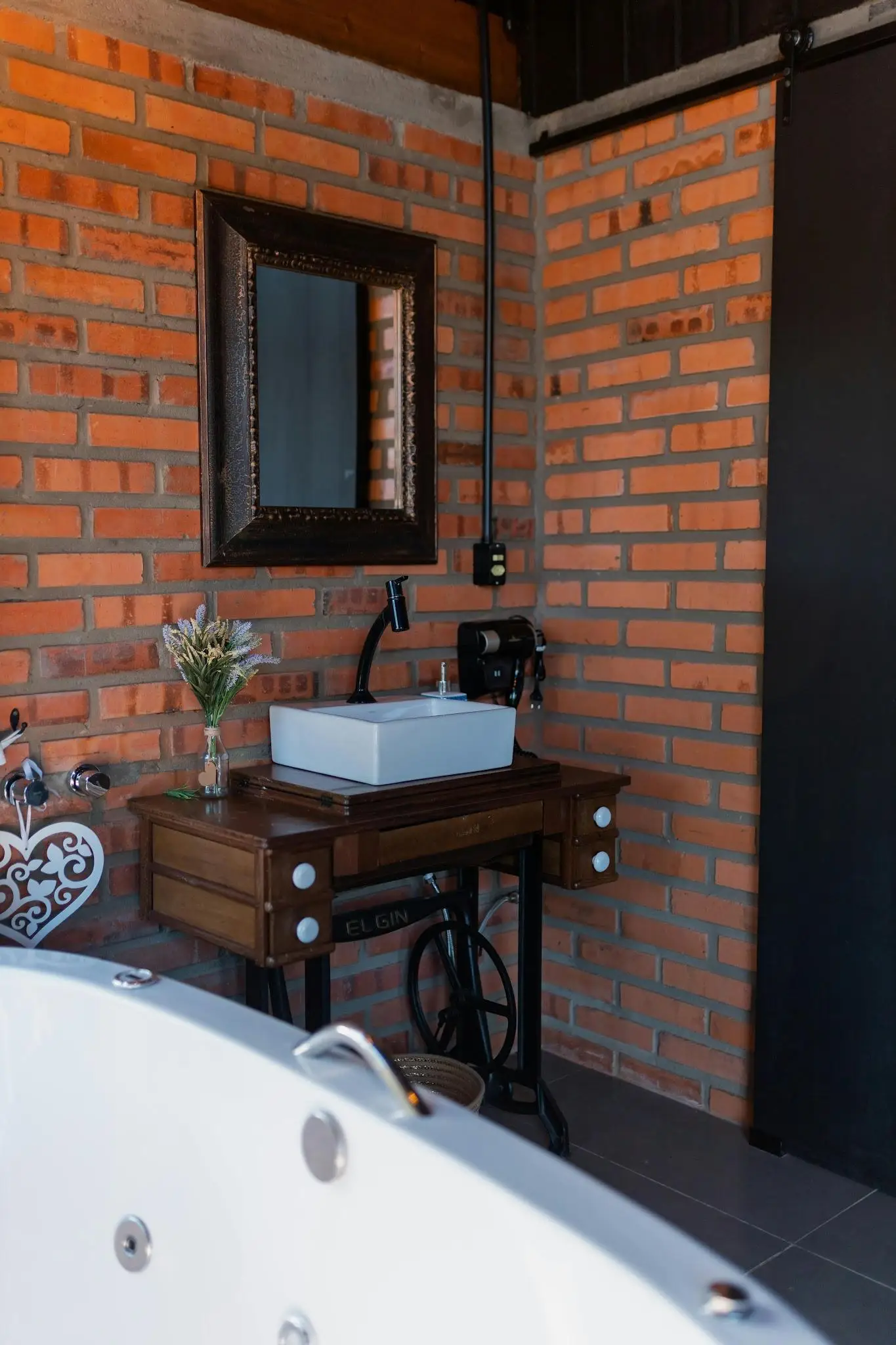 Rustic bathroom with brick walls, wooden vanity, and rectangular mirror above white basin sink