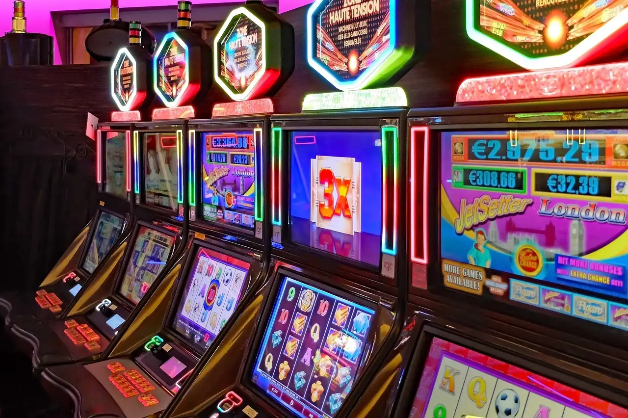 Row of illuminated slot machines in a colorful casino setting with neon lights