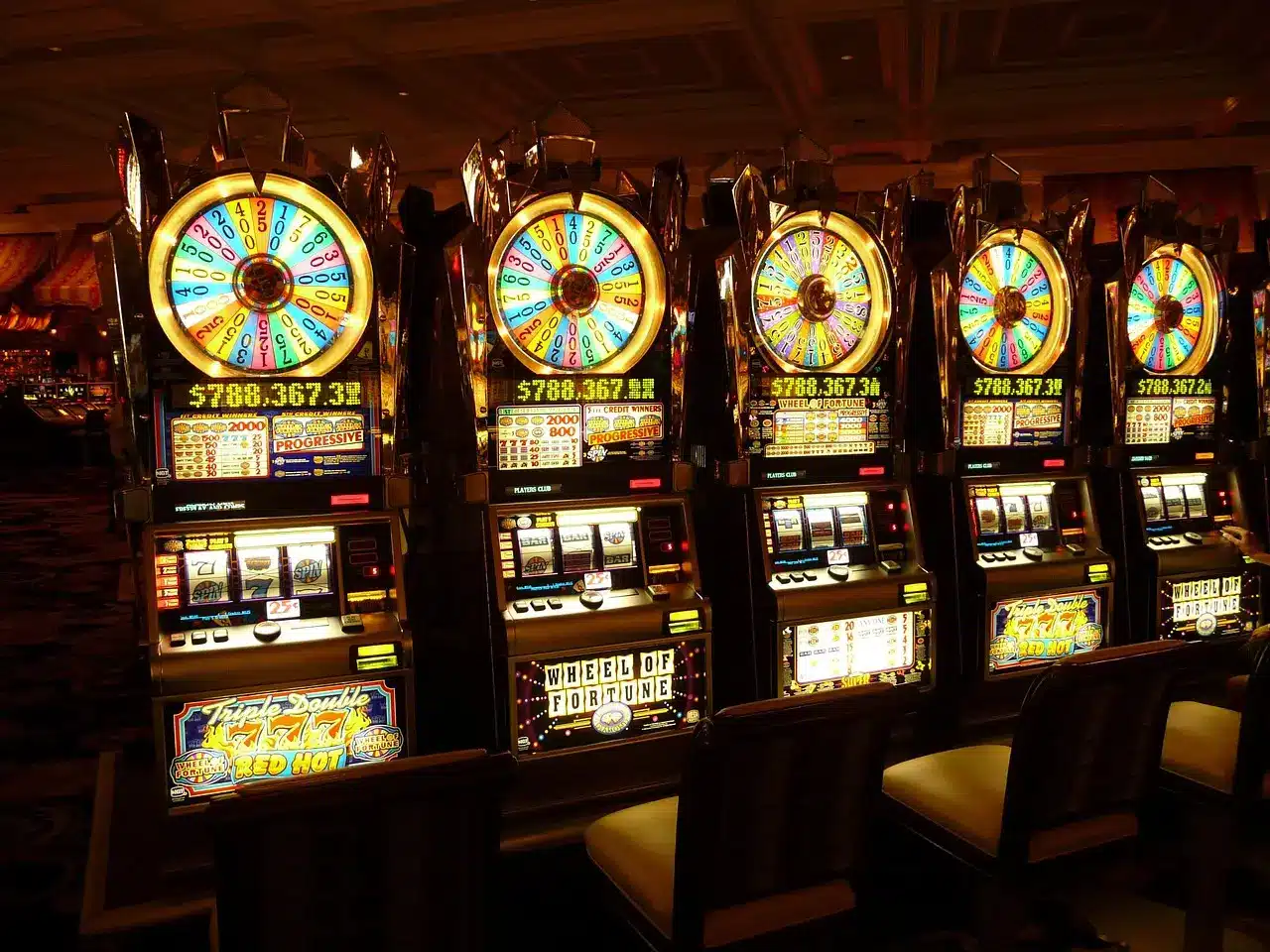 Row of illuminated slot machines in a dimly lit casino setting