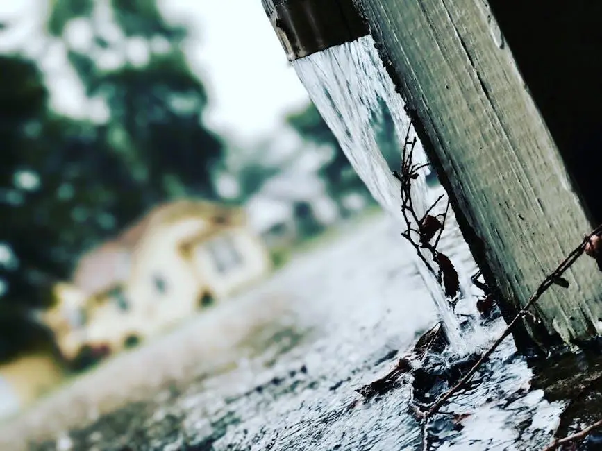 Rainwater cascading from gutter against blurred suburban house backdrop