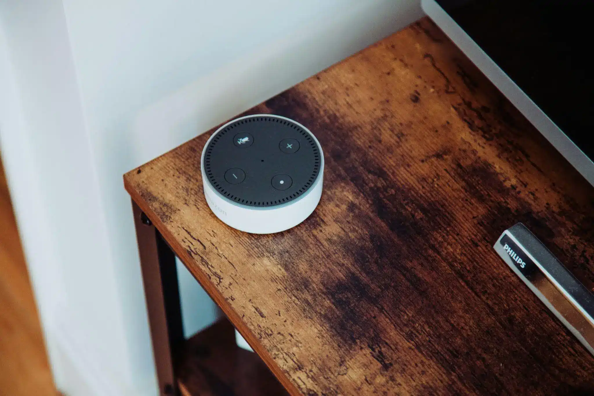 Smart speaker on rustic wooden table beside television in cozy living room setting