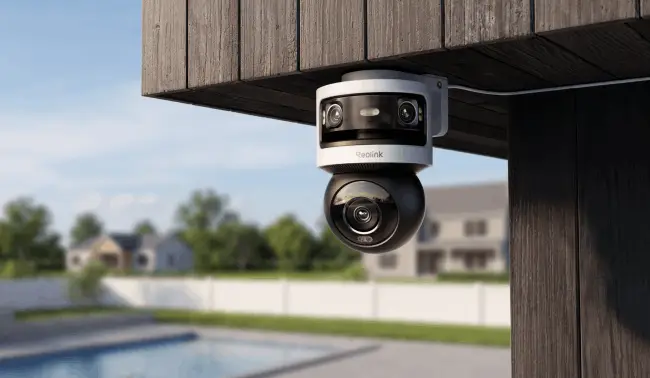 Outdoor security camera mounted on wooden structure overlooking backyard with lawn and houses