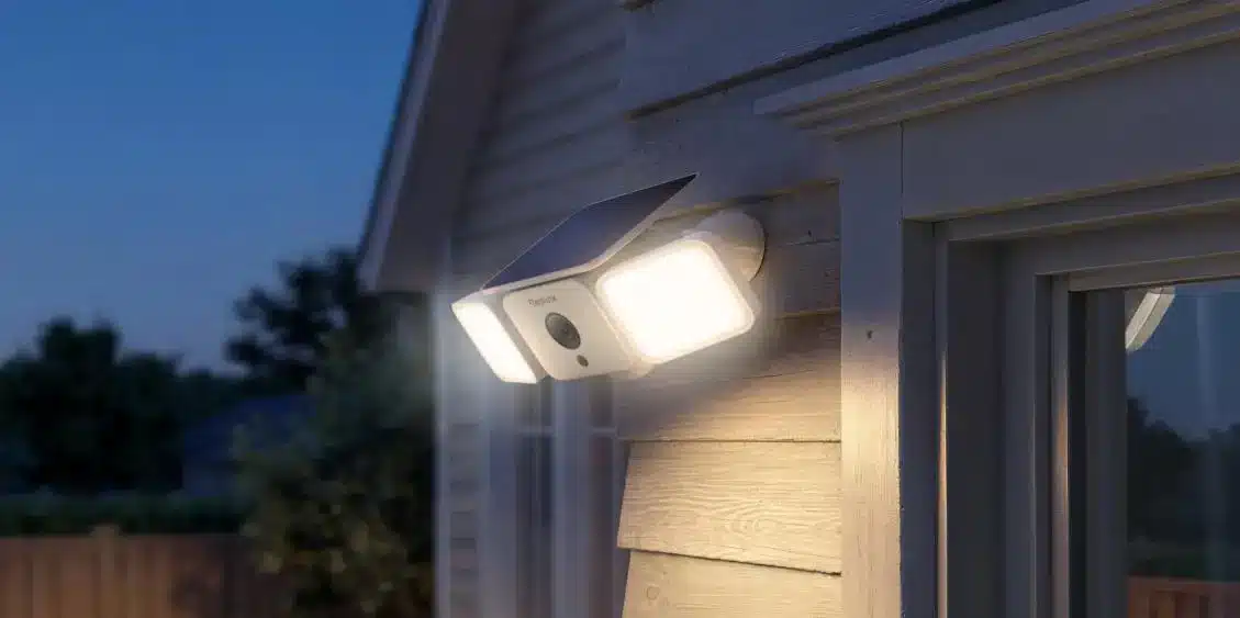 Outdoor security camera with LED lights mounted on house exterior at dusk