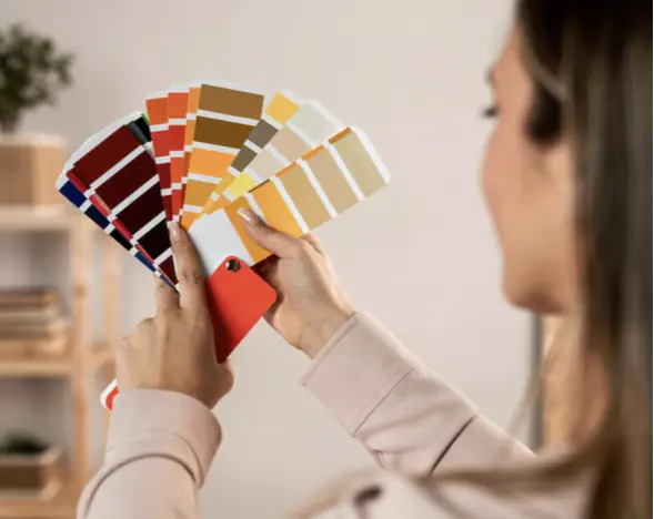Woman selecting from colorful paint swatches in softly lit room