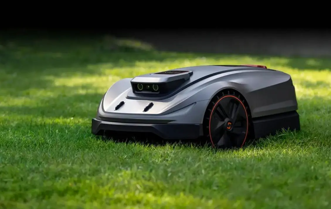 Robotic lawn mower on grass in an outdoor setting with sleek design and black accents