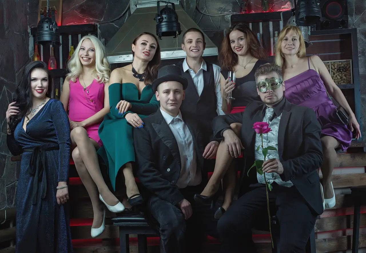 Group of people dressed in formal wear posing in a dimly lit room
