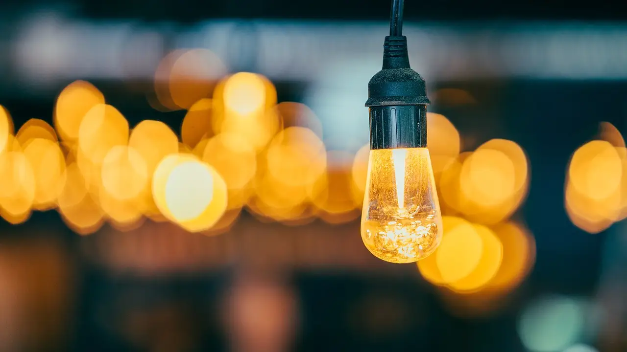 Hanging Edison bulb glowing warmly with blurred bokeh lights in the background