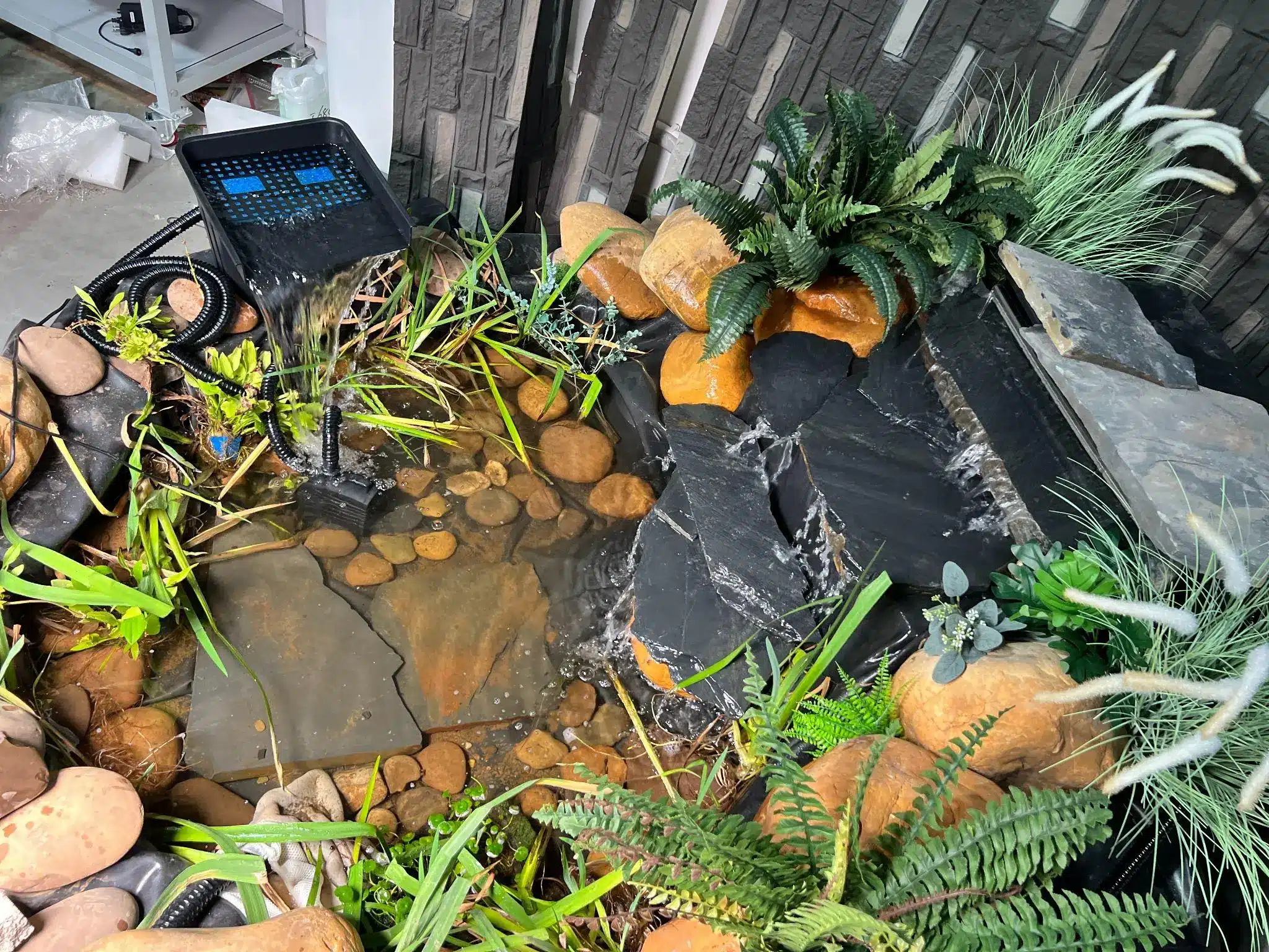 Water feature with stones and plants in an indoor setting with flowing stream