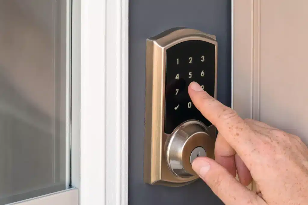 Hand entering code on smart door lock with brushed metal finish and numeric keypad