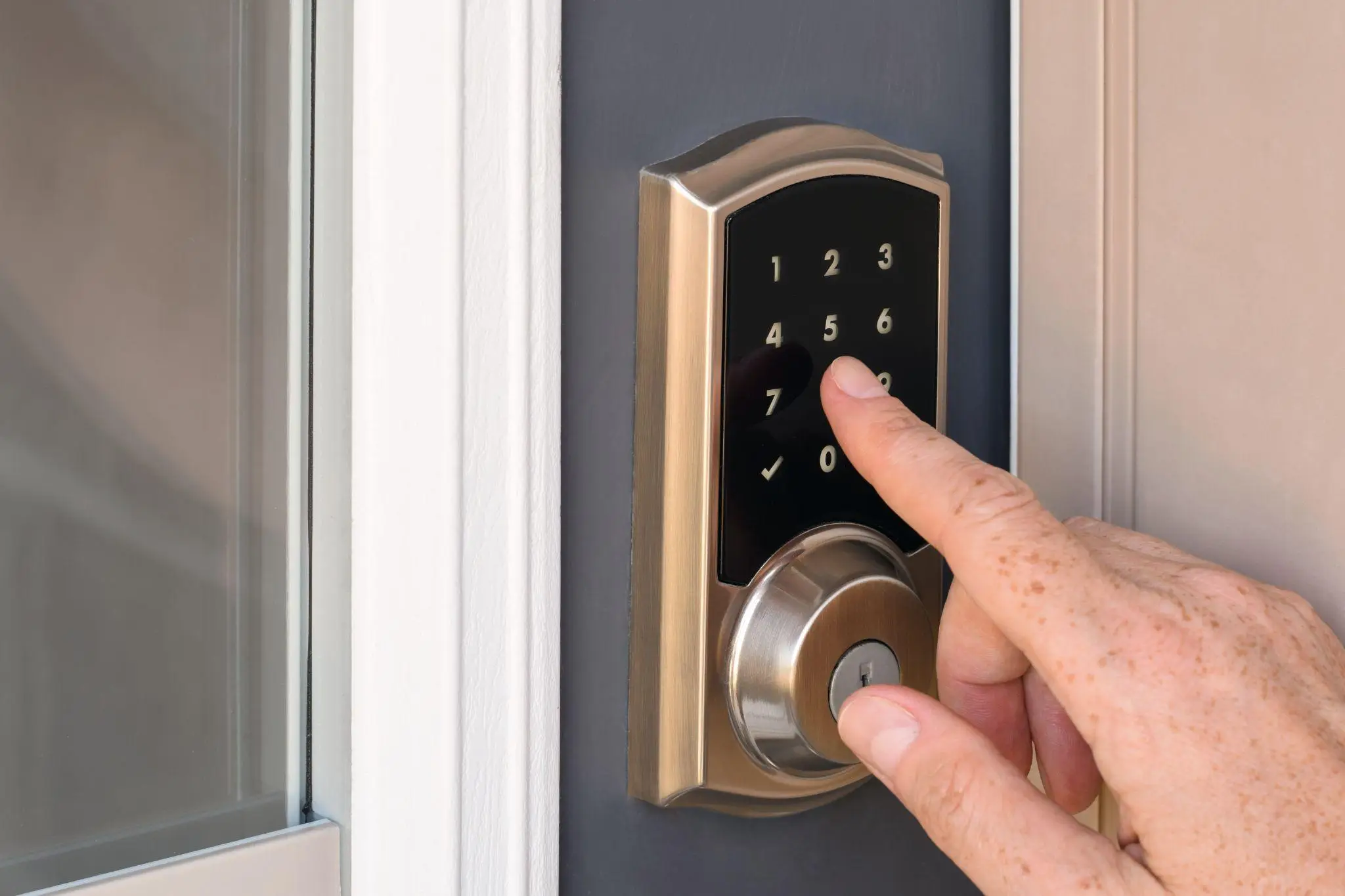Hand entering code on smart door lock with brushed metal finish and numeric keypad