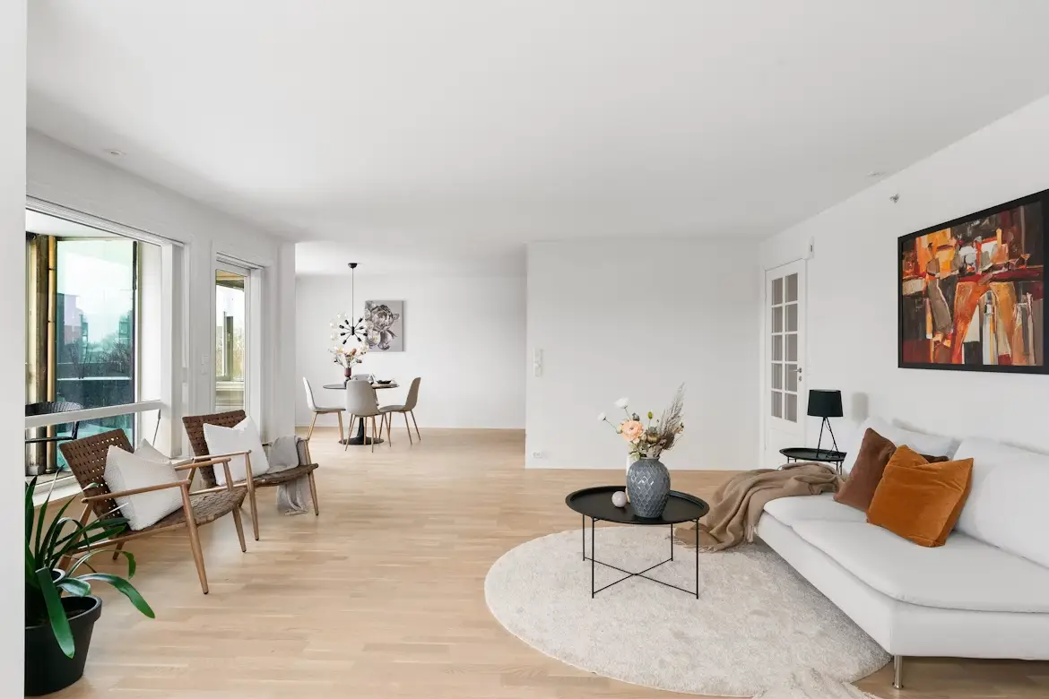 Spacious living room with modern white sofa, abstract art, and dining area in open-plan apartment