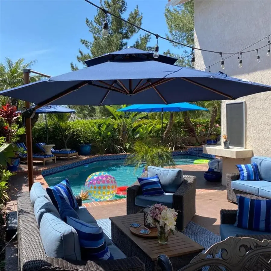 Outdoor seating area with blue cushioned chairs and umbrella by a pool with inflatable ball