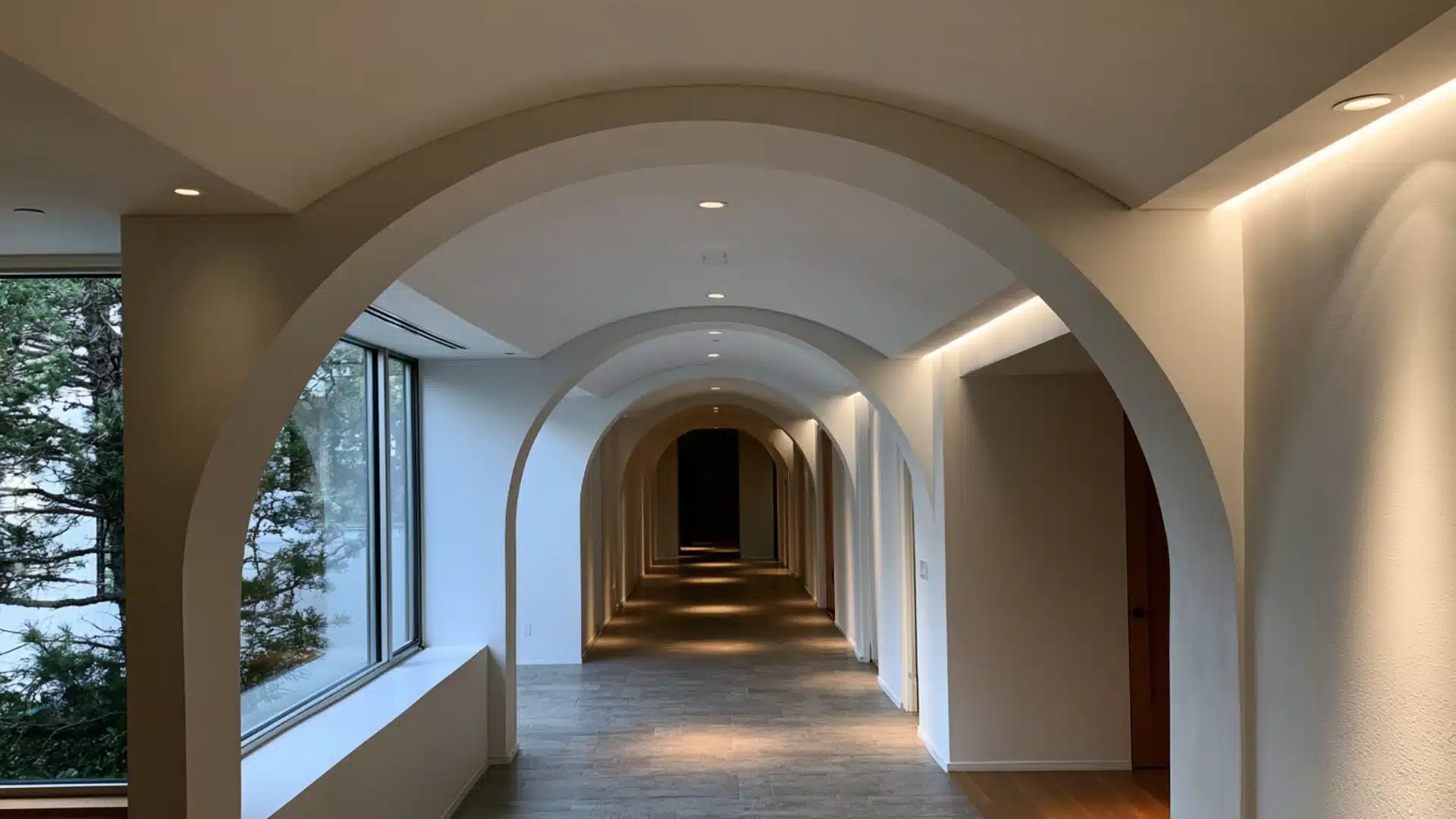 curved white barrel vault ceiling hallway with a large window and warm lighting