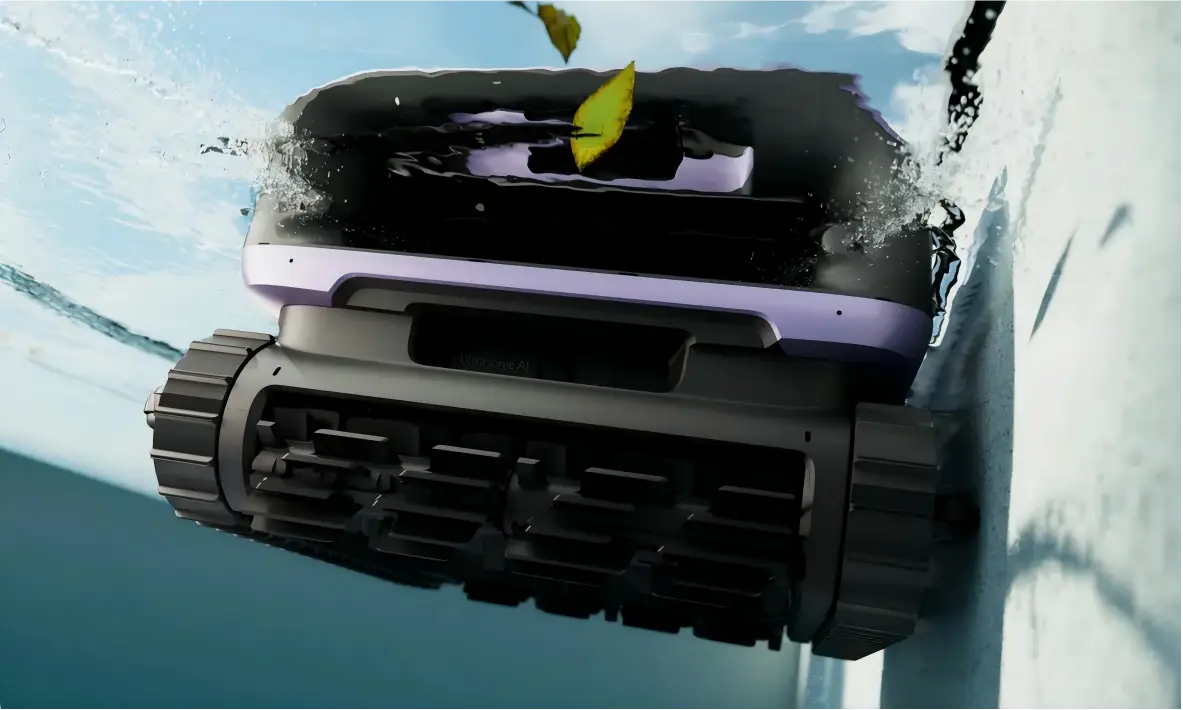 Underwater robotic pool cleaner rolling along pool wall with floating leaves